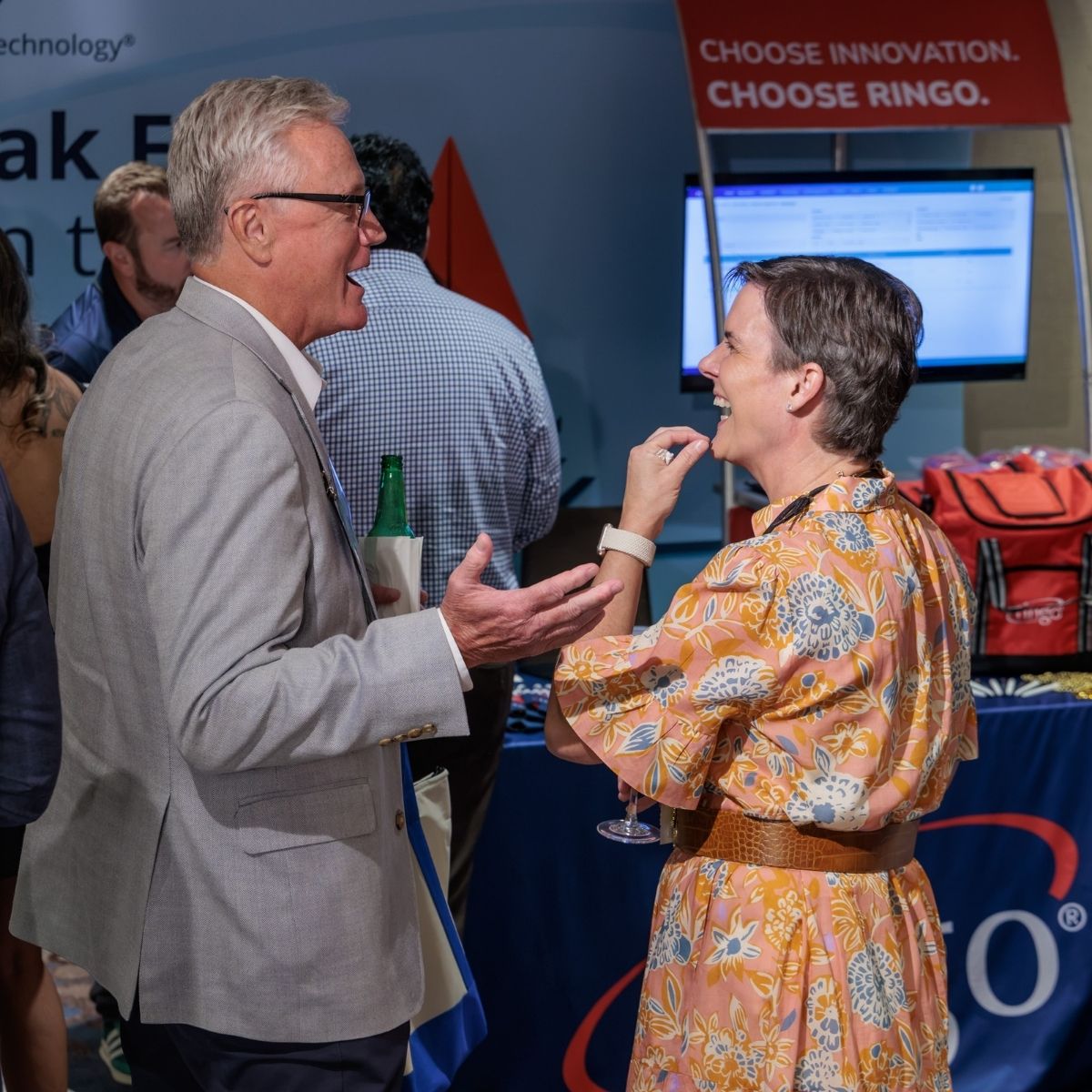 Ringo team member laughing with an attendee in front of the Choose Innovation. Choose Ringo. booth banner at the 2026 NALTO Fall Fly-In
