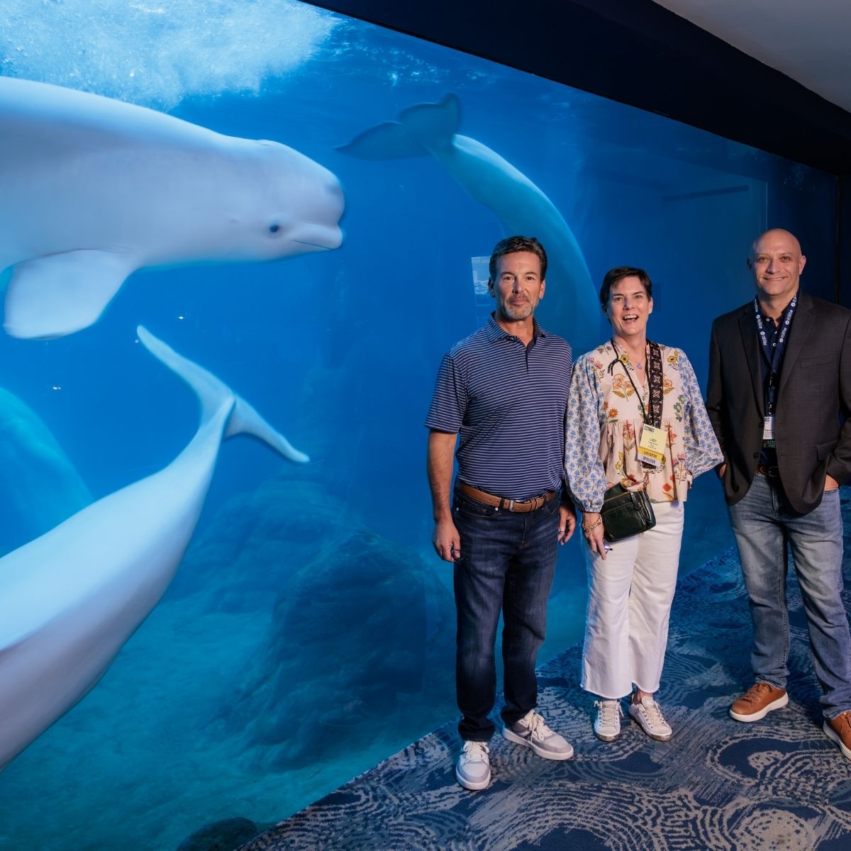 Fly-In attendees smiling in front of a beluga whale habitat in Atlanta
