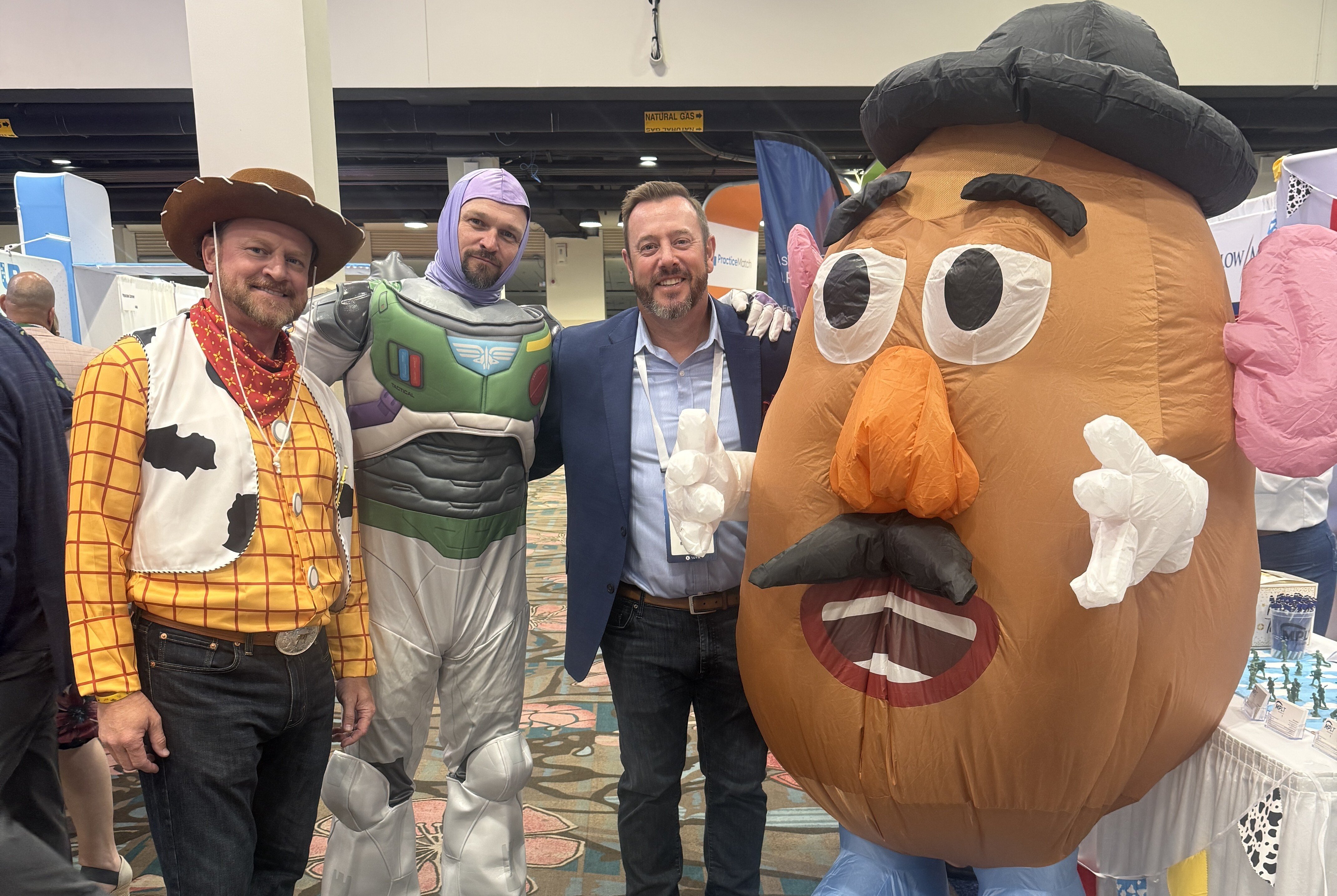 AAPPR conference attendees posing with Toy Story characters on exhibit floor, creating a fun and engaging networking experience.