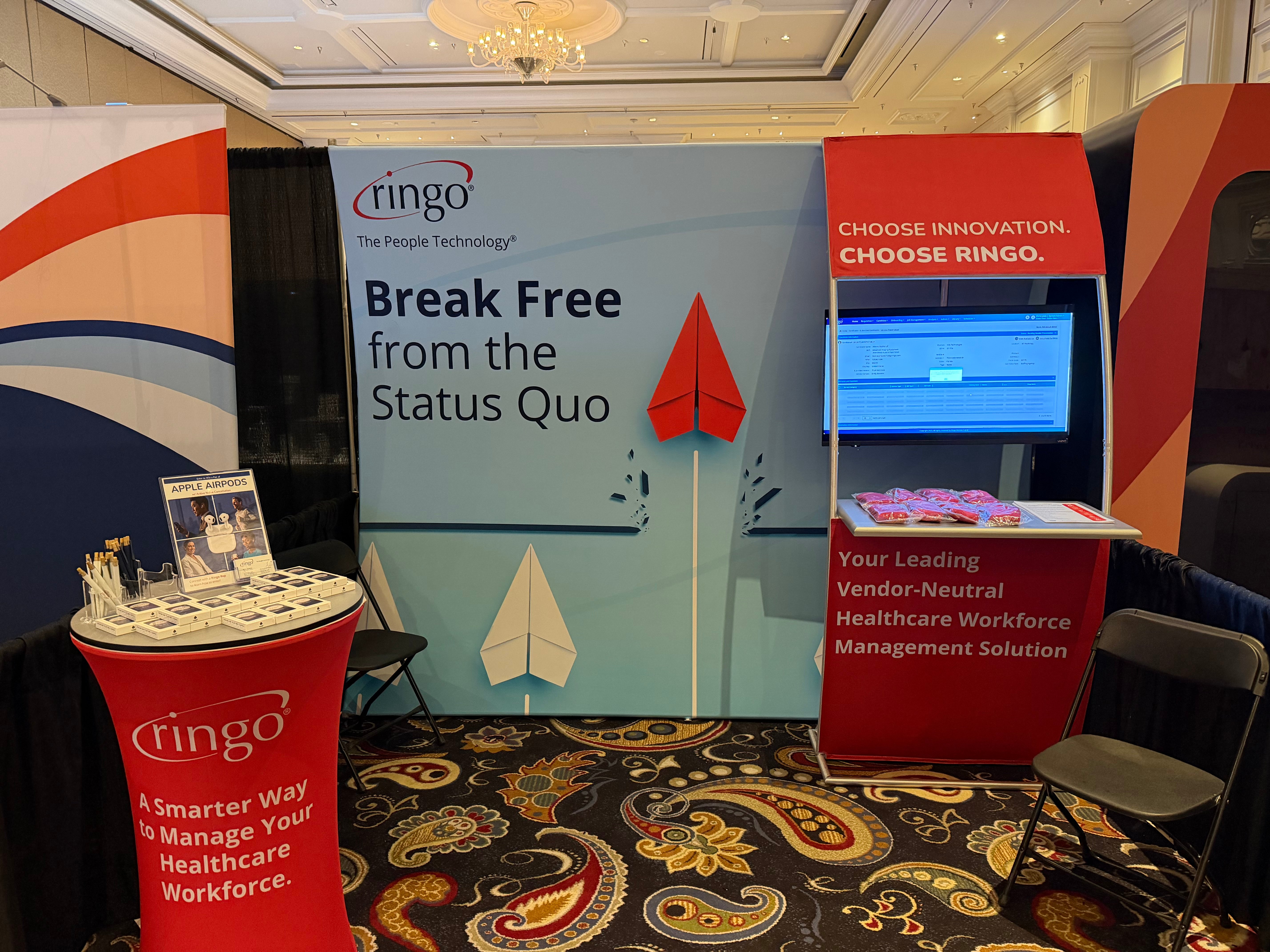 Ringo booth at NALTO/NAPR Conference at the Bellagio Las Vegas featuring vendor-neutral healthcare workforce management platform, live VMS demo screen, branded signage reading “Break Free from the Status Quo,” and healthcare staffing solutions display.